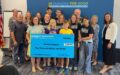 Children and adults holding a giant check made out to Ruckus Inspires from the Community Foundation