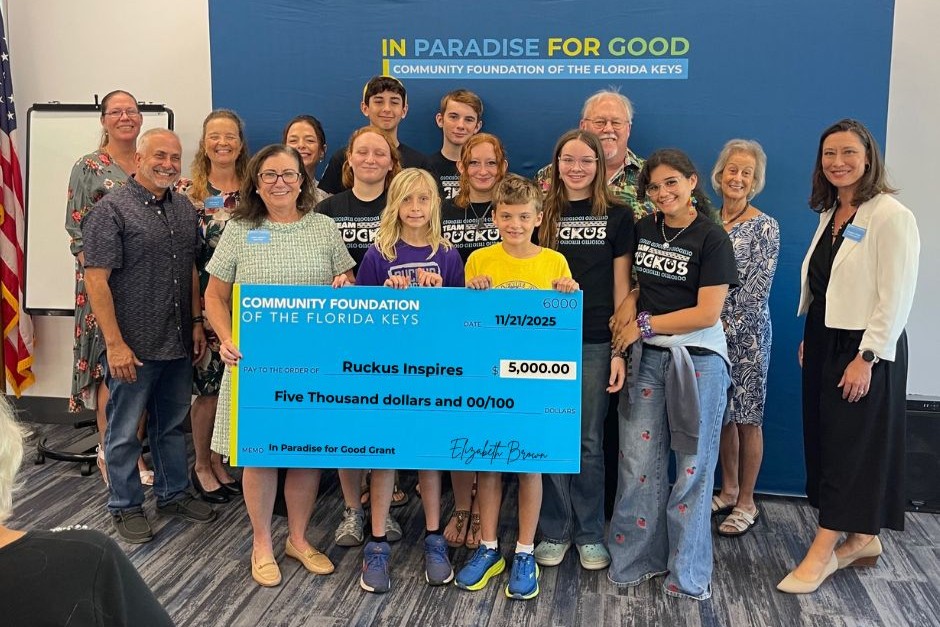 Children and adults holding a giant check made out to Ruckus Inspires from the Community Foundation